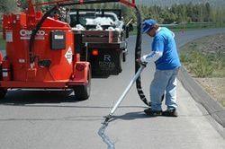 Close-up of hot rubberized crack sealant being applied.